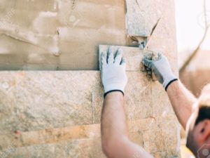 77409978-mason-worker-installing-stone-tiles-on-wall-on-construction-site-1024x683